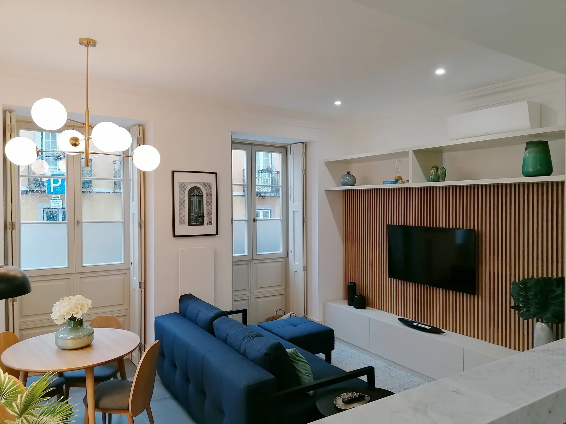 Una sala luminosa con asientos azules y un televisor montado en la pared.