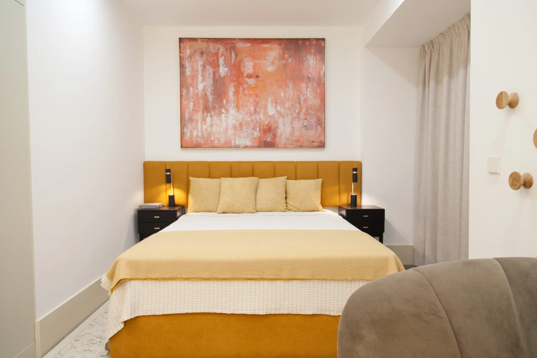 Dormitorio con una cama, mesillas de noche y una obra abstracta sobre el cabecero.