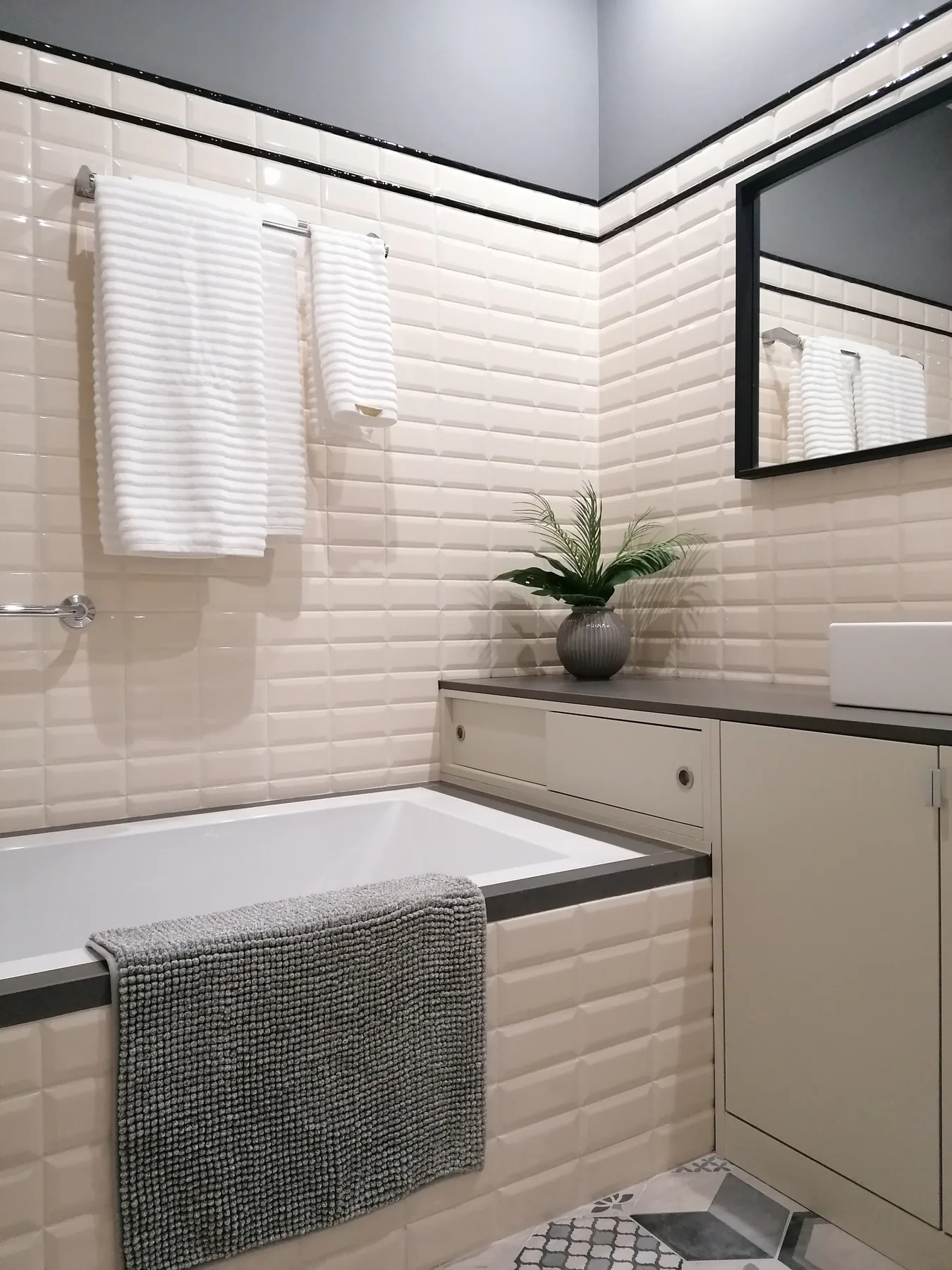 Un baño alicatado con bañera y una encimera con lavabo.