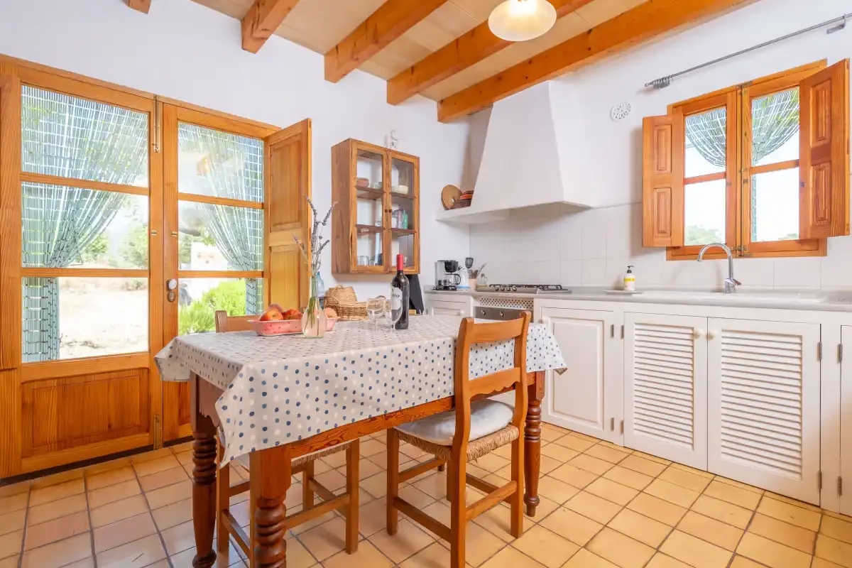 A bright kitchen with a dining table and wooden-framed windows.
