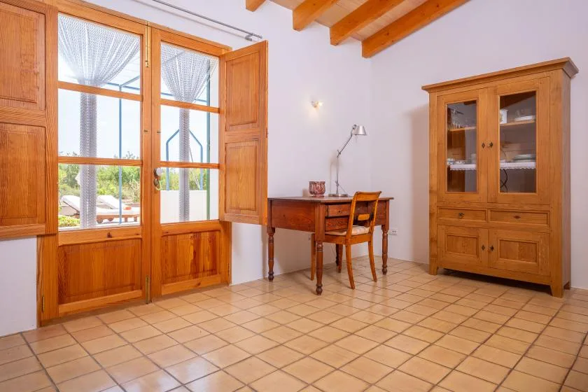 A bright room with wooden windows, a desk, and a cabinet.