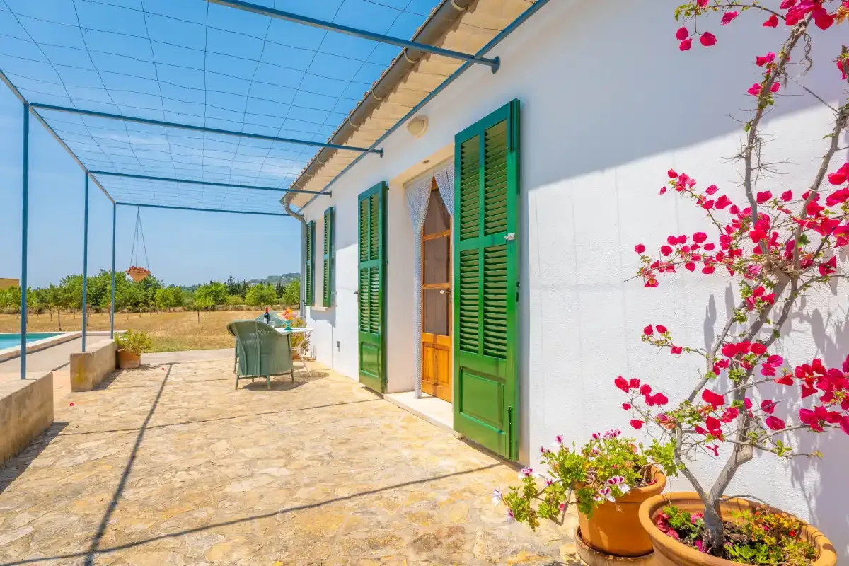 A sunny outdoor terrace with green shutters and a canopy overhead.