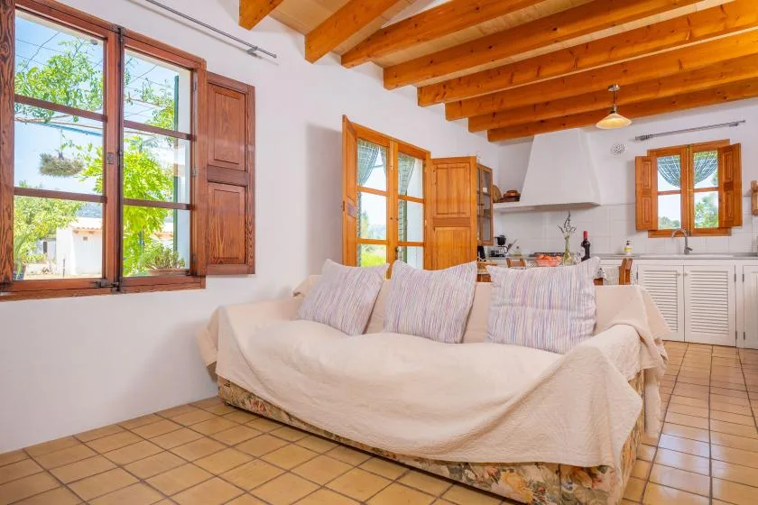 A bright living room with a covered seating area and wooden ceiling beams.