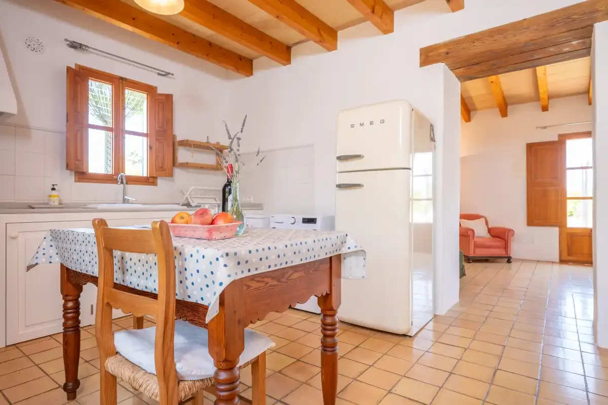 A kitchen dining area with a wooden table and a refrigerator.