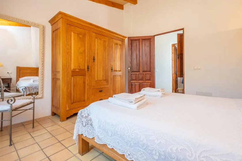 A bedroom with a large wooden wardrobe and a neatly made bed.