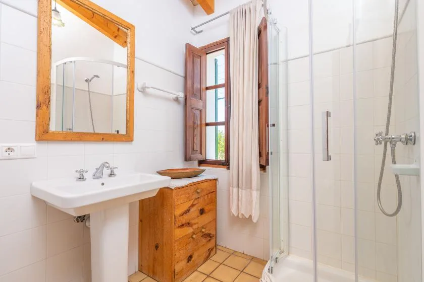 A bright bathroom with a sink, wooden vanity, and glass shower.