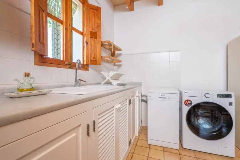 A bright laundry room with a washing machine beside a long countertop.