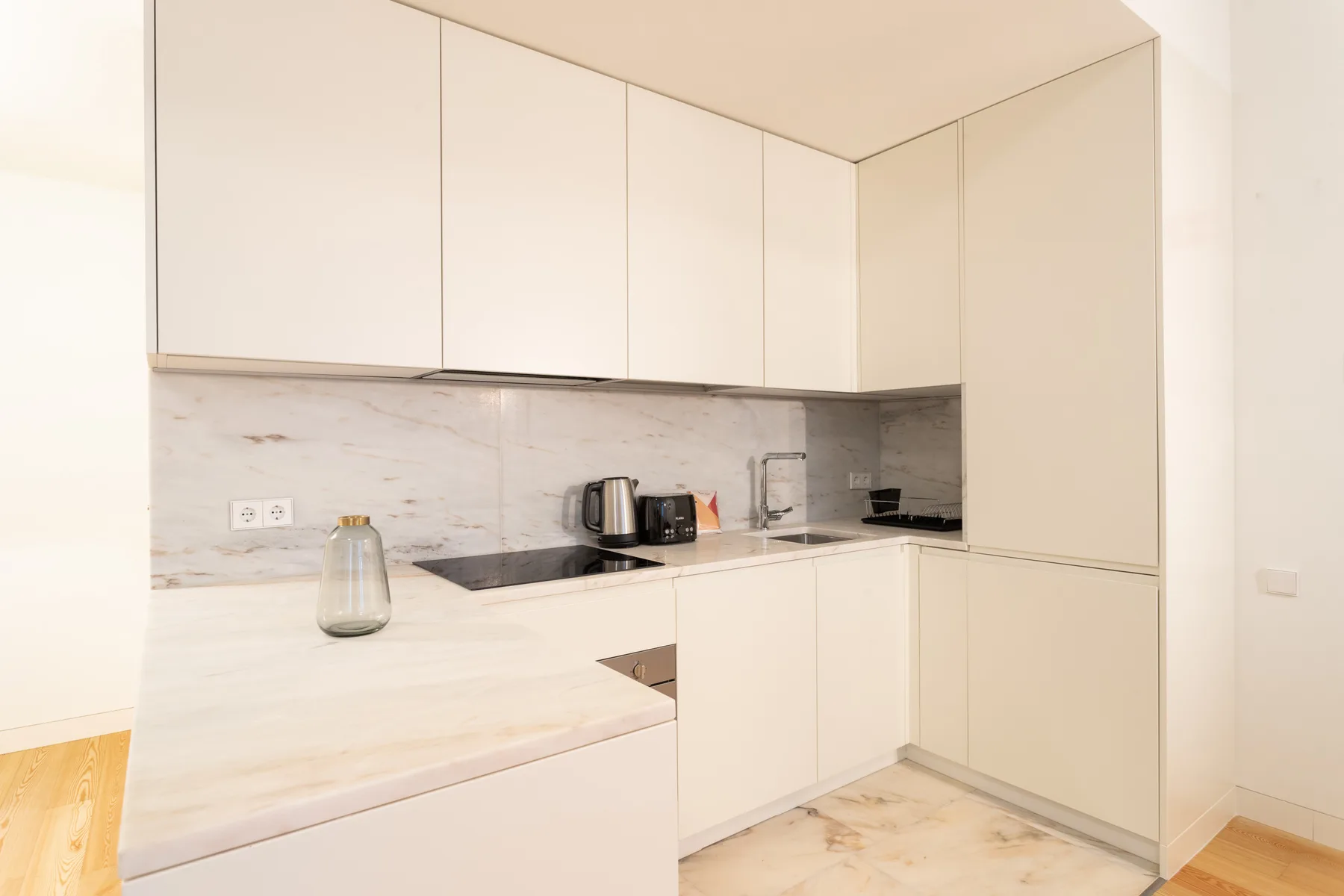 A modern kitchen with pale cabinets and a light countertop.