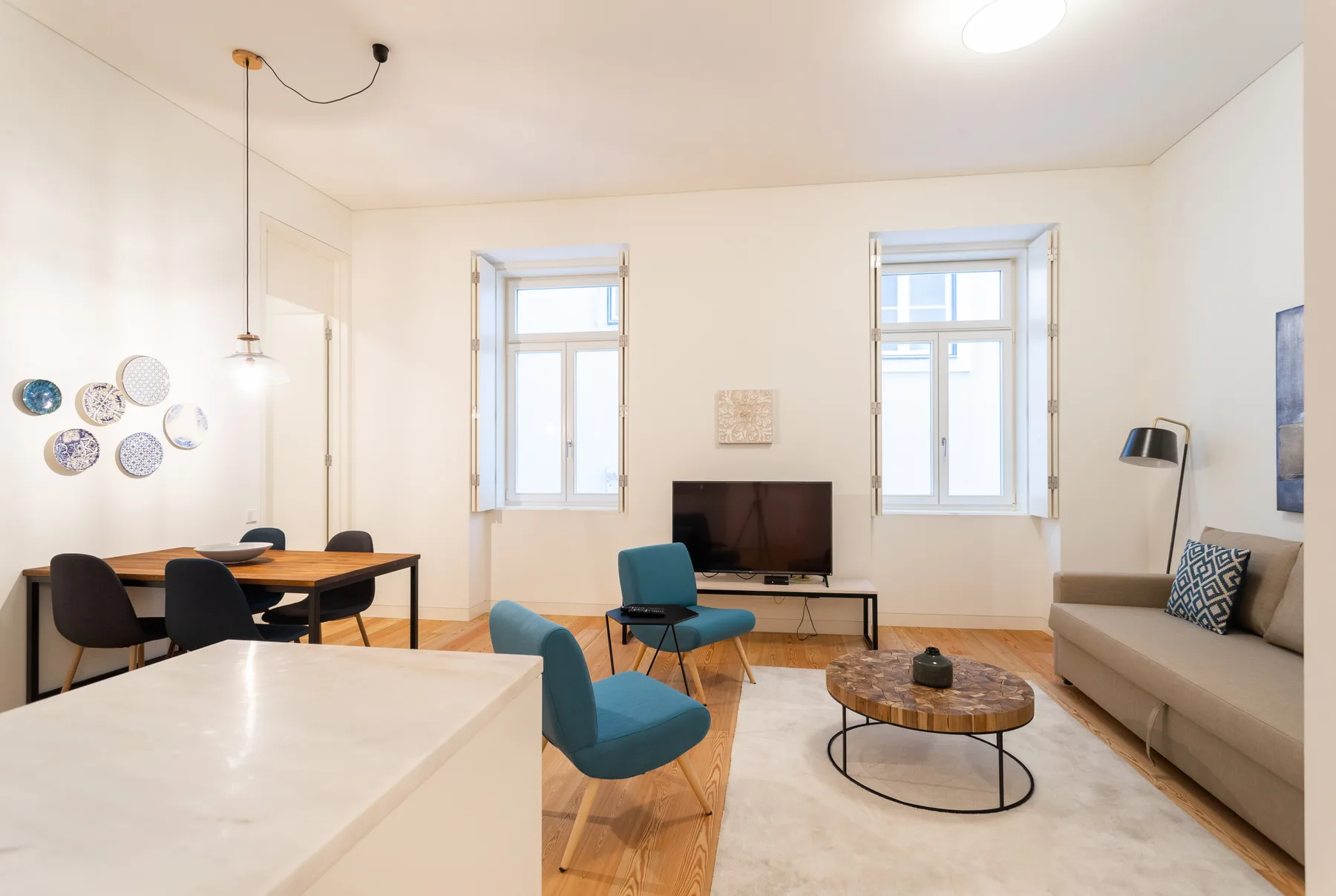 A bright living and dining room with a television and seating.
