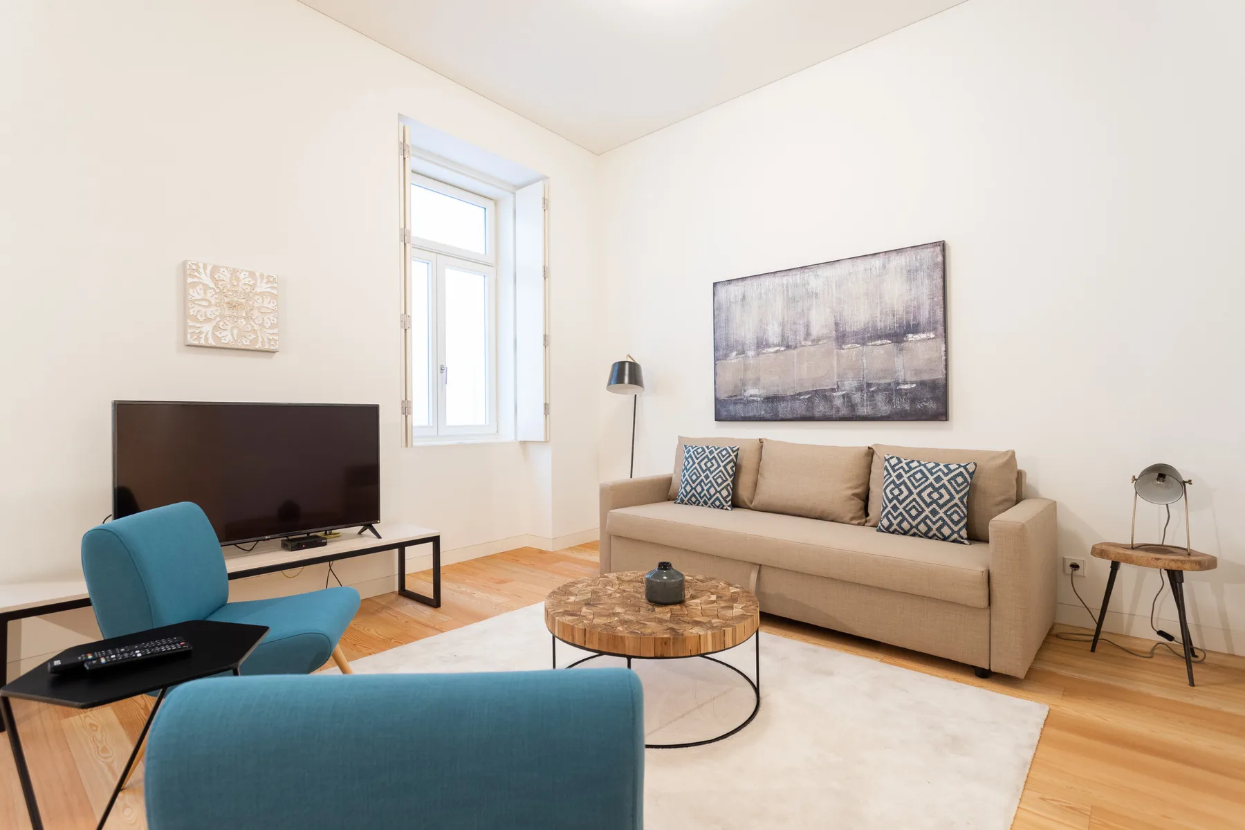 A living room with a beige sofa, television, and blue seating.