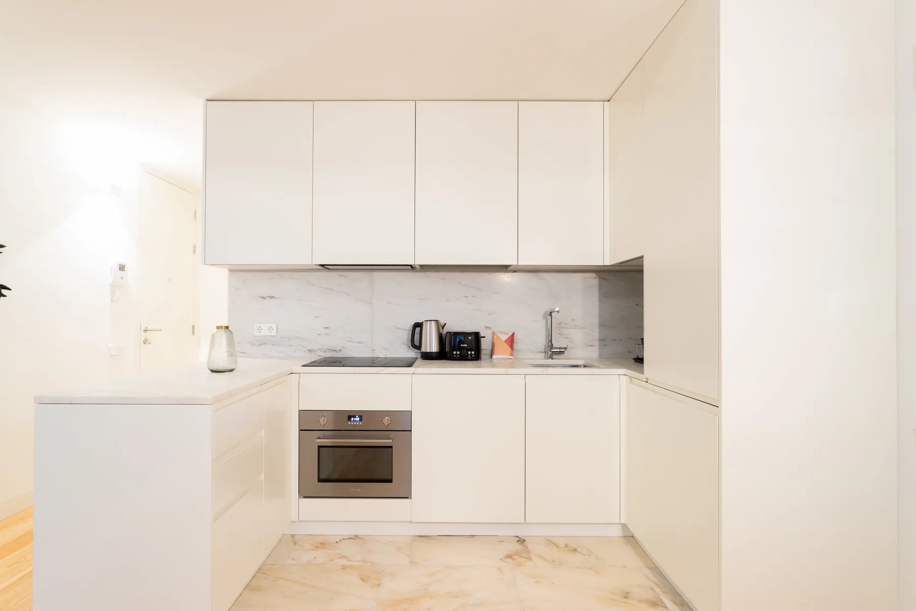 A bright modern kitchen with white cabinets and a built-in oven.