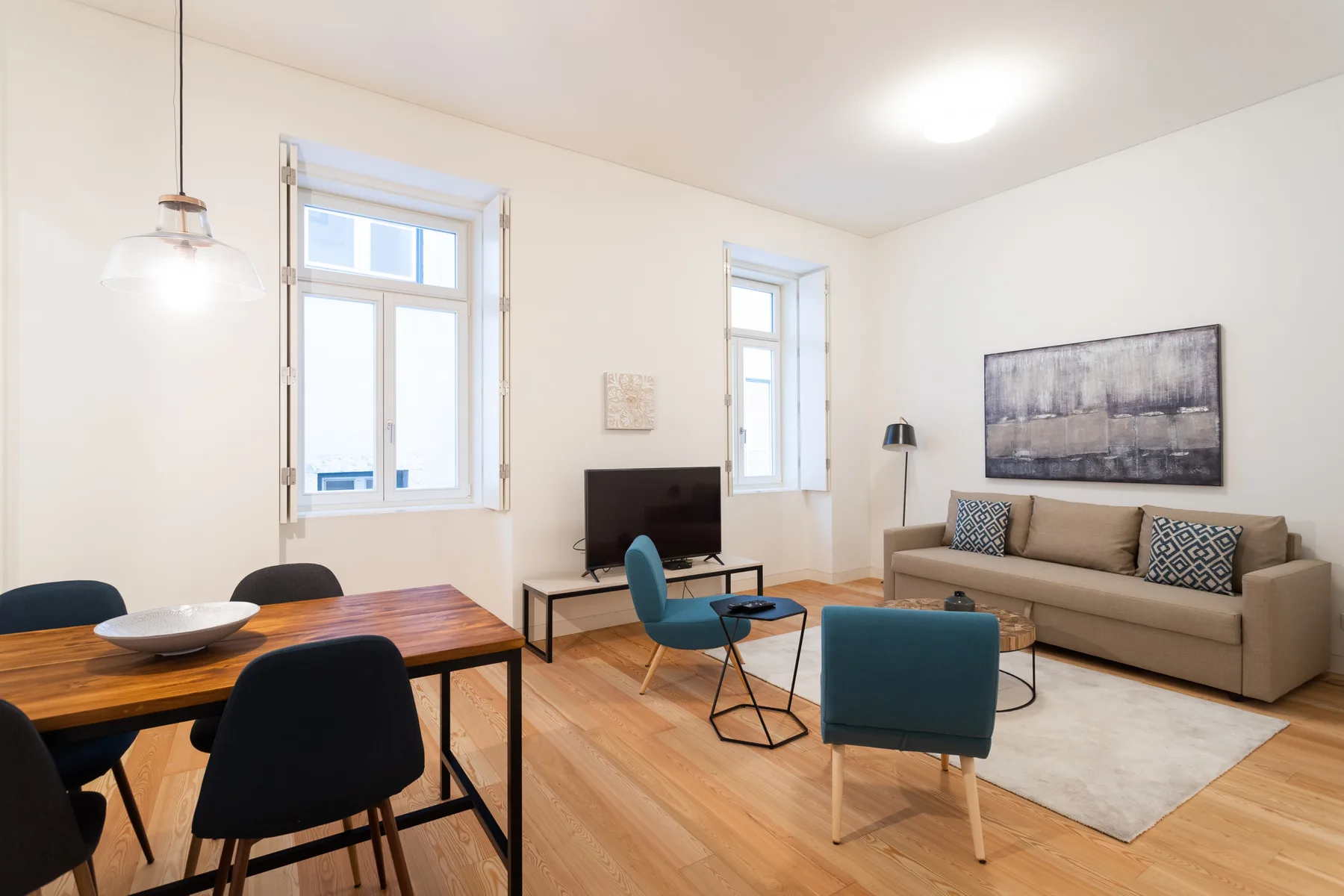 A bright living room with a dining table, seating, and a television.