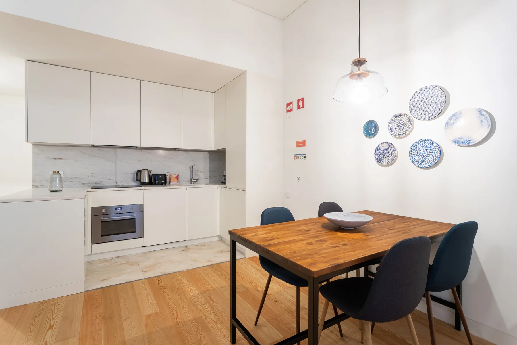 A dining area with a wooden table sits beside a compact kitchen.