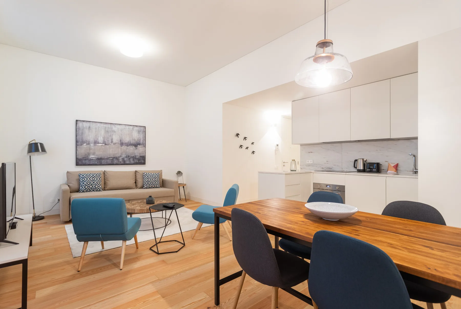 A combined living and dining area with a kitchen and wooden dining table.