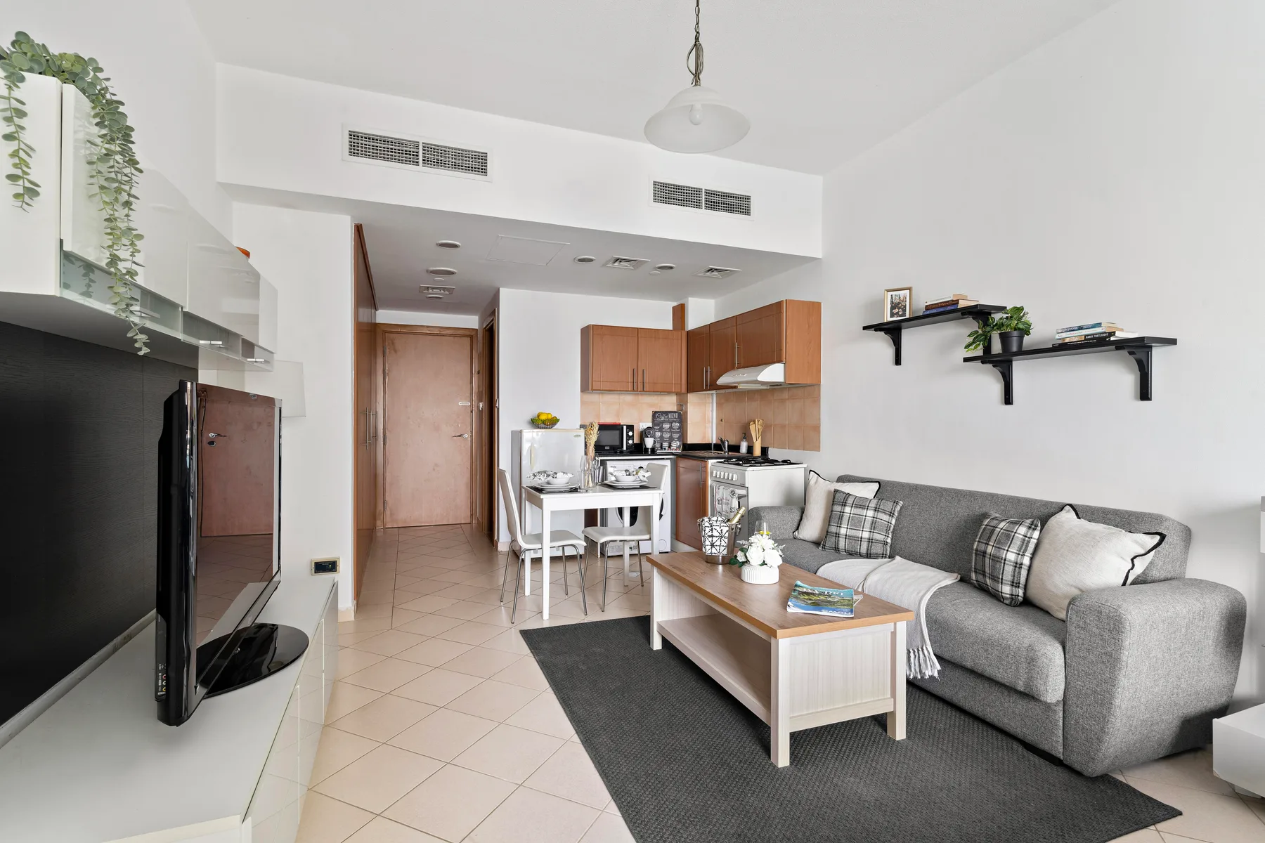 A bright living room with a gray seating area, coffee table, and open kitchen.