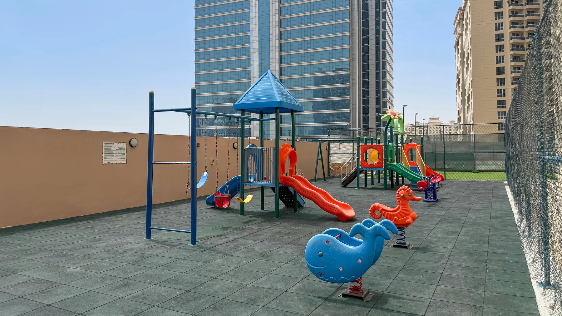 A rooftop playground has colorful climbing structures and animal-shaped play equipment.