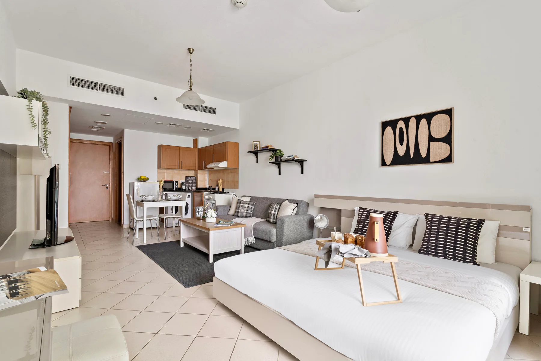 A bright open-plan living and sleeping area with a kitchenette in the background.