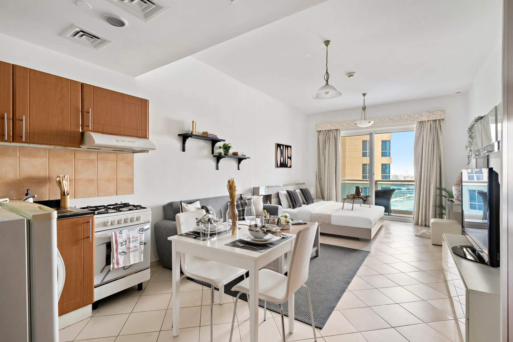 An open-plan living and dining area with a compact kitchen and large windows.