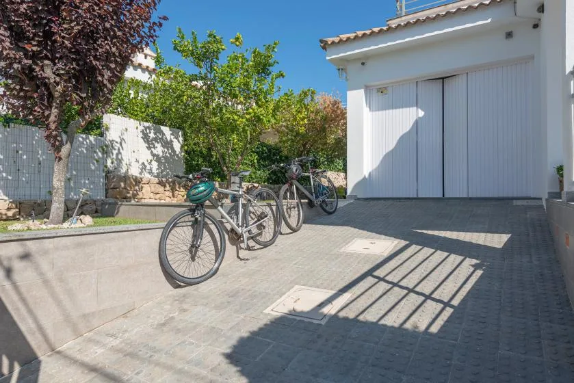 A paved outdoor area with bicycles beside a large white garage door.