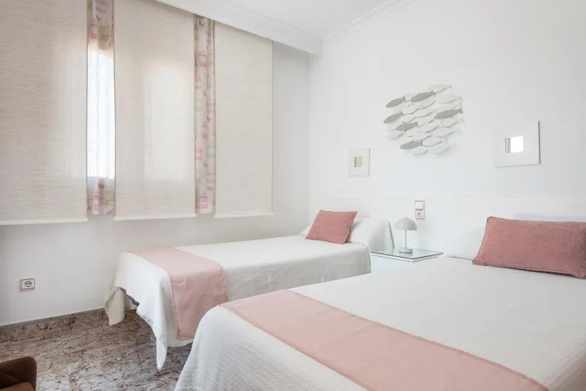 A bright bedroom with two beds and pale pink accents.