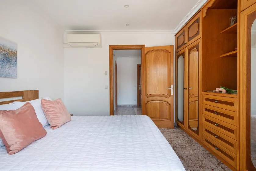 A bedroom with a bed beside wooden wardrobes and an open doorway.