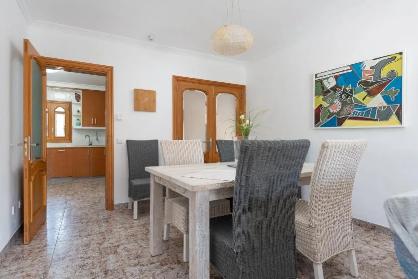 A dining room with a table and woven seating beside an open doorway.