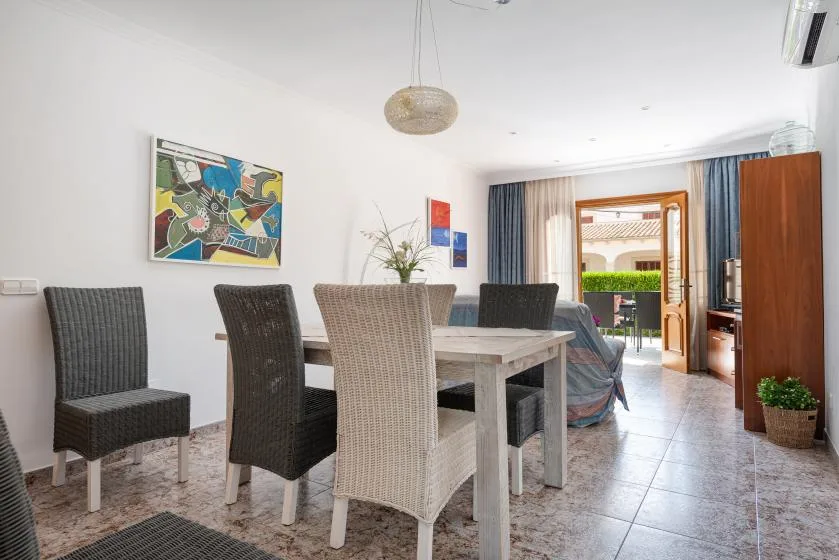 A dining area with a table and seating beside an open balcony doorway.