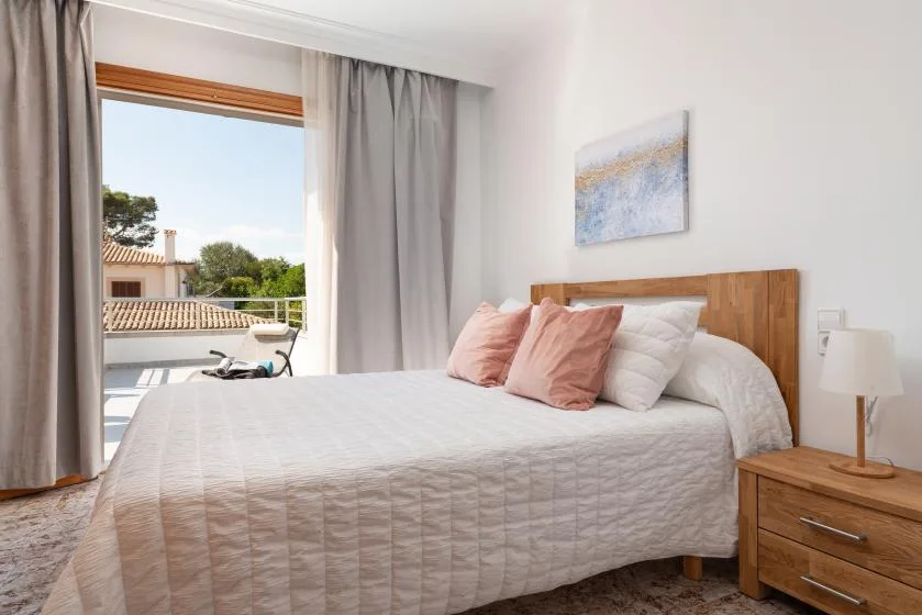 A bedroom with a bed beside an open window and gray curtains.