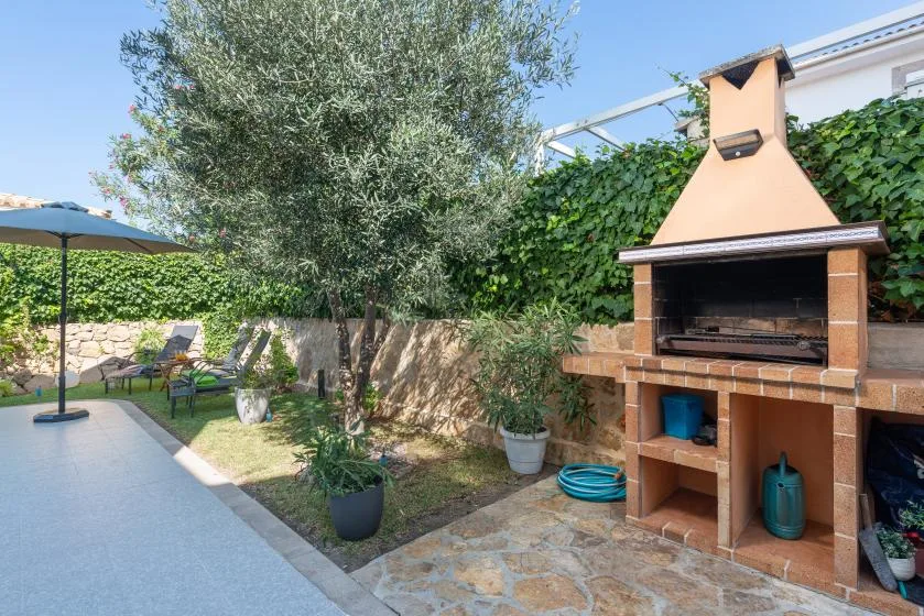 An outdoor patio with a built-in barbecue beside a small garden.