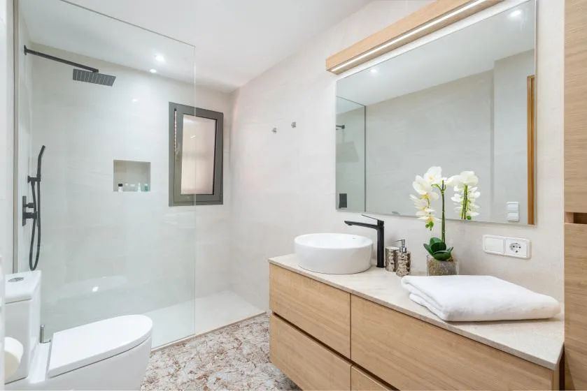 A bright bathroom with a glass shower, vanity, and white basin.