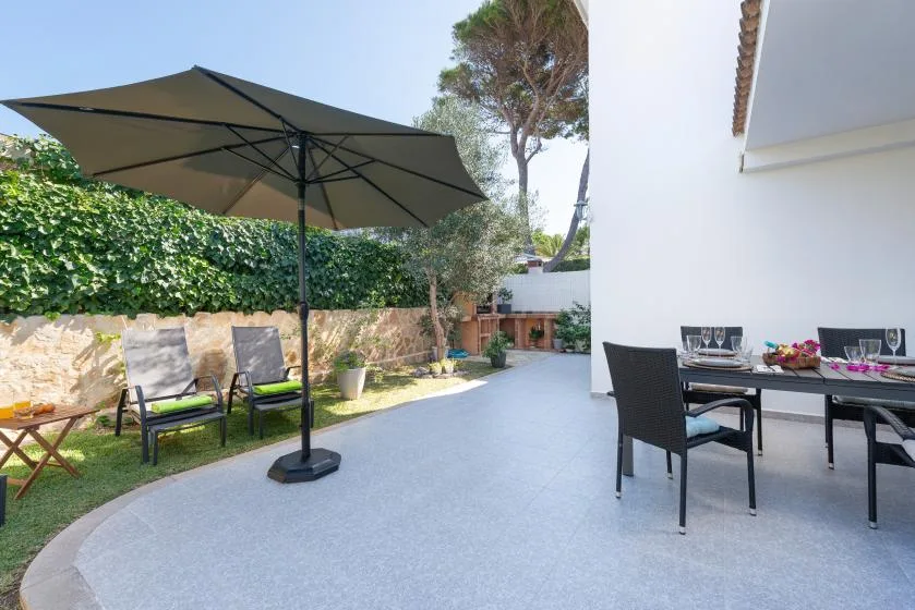 An outdoor patio with a large umbrella, seating, and a dining table.