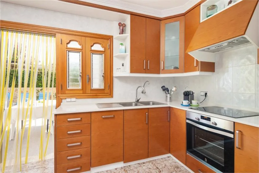 A bright kitchen with wooden cabinets, a sink, and an oven.