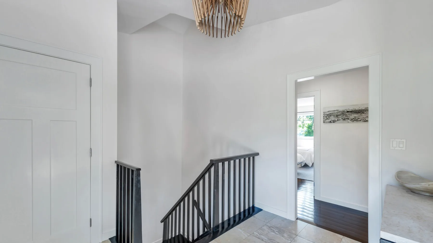 Un pasillo luminoso se abre a una escalera y a una puerta hacia otra habitación.