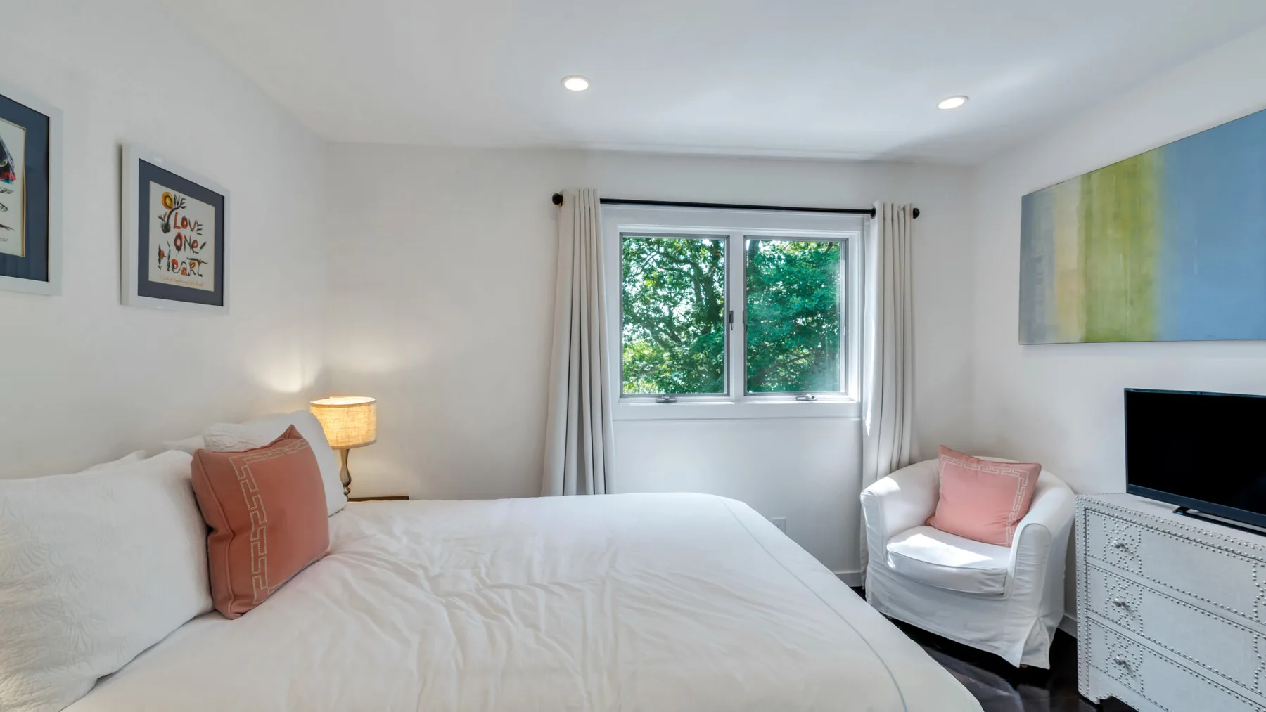Un dormitorio con una cama grande, una ventana y un sillón acolchado.