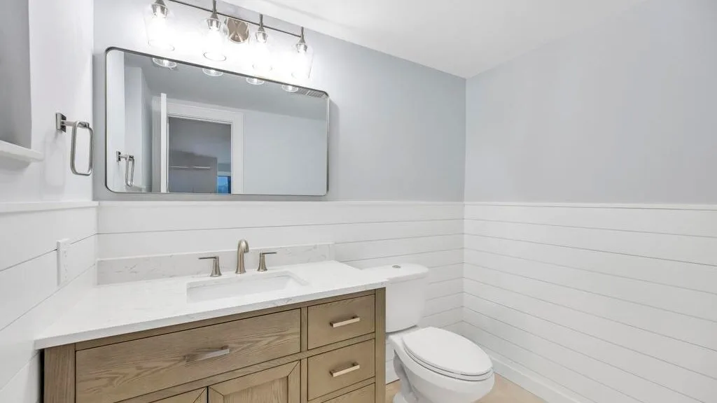 Un baño luminoso con un lavabo amplio, espejo e inodoro.