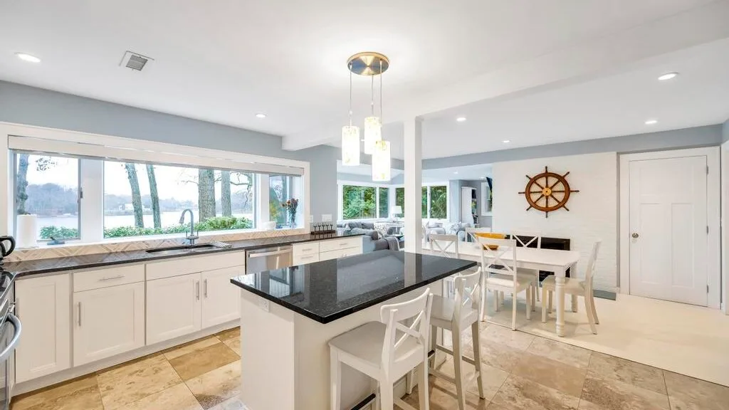 Una cocina luminosa con una isla central y una mesa de comedor junto a las ventanas.