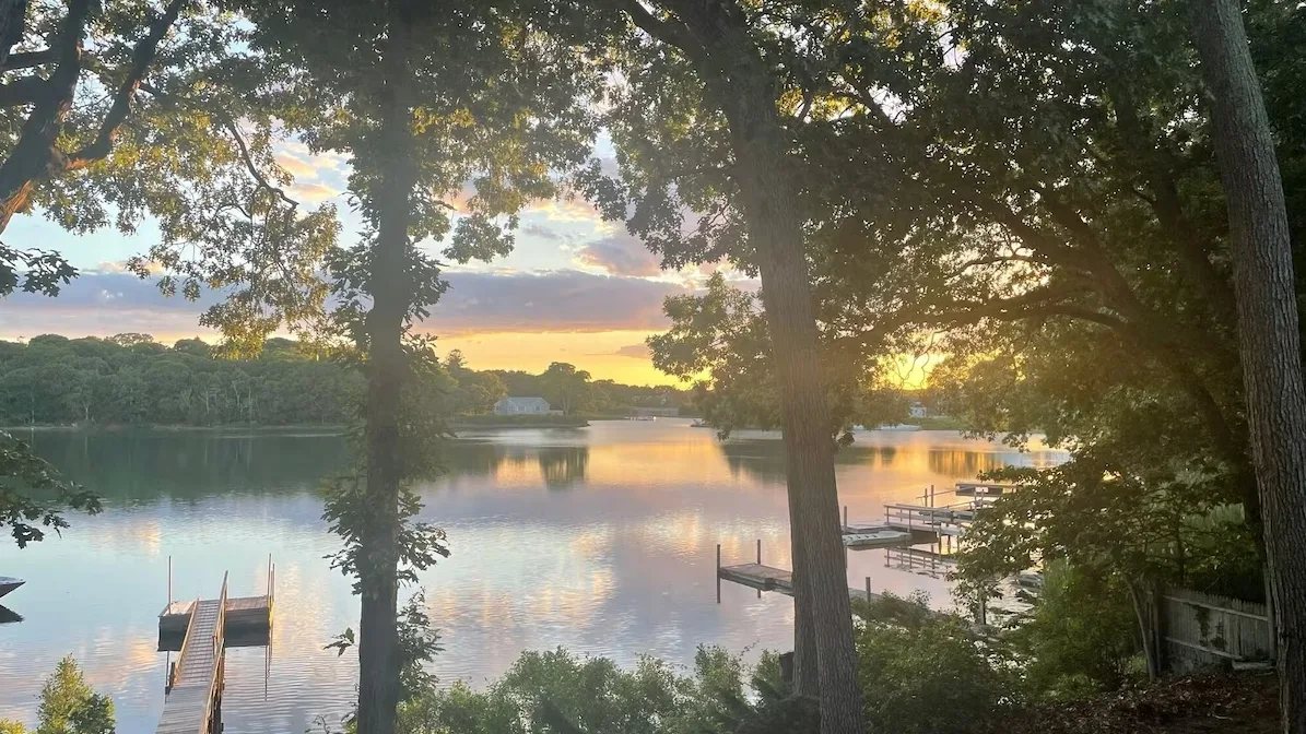 Un lago al atardecer, enmarcado por árboles junto a la orilla.