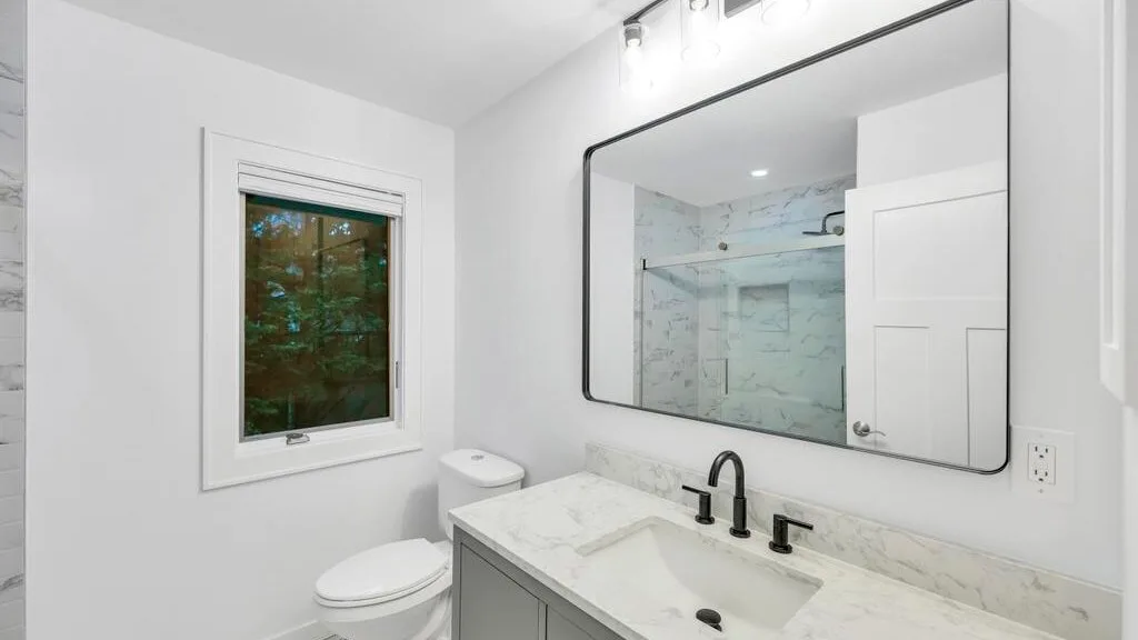 Un baño luminoso con lavabo, espejo e inodoro.