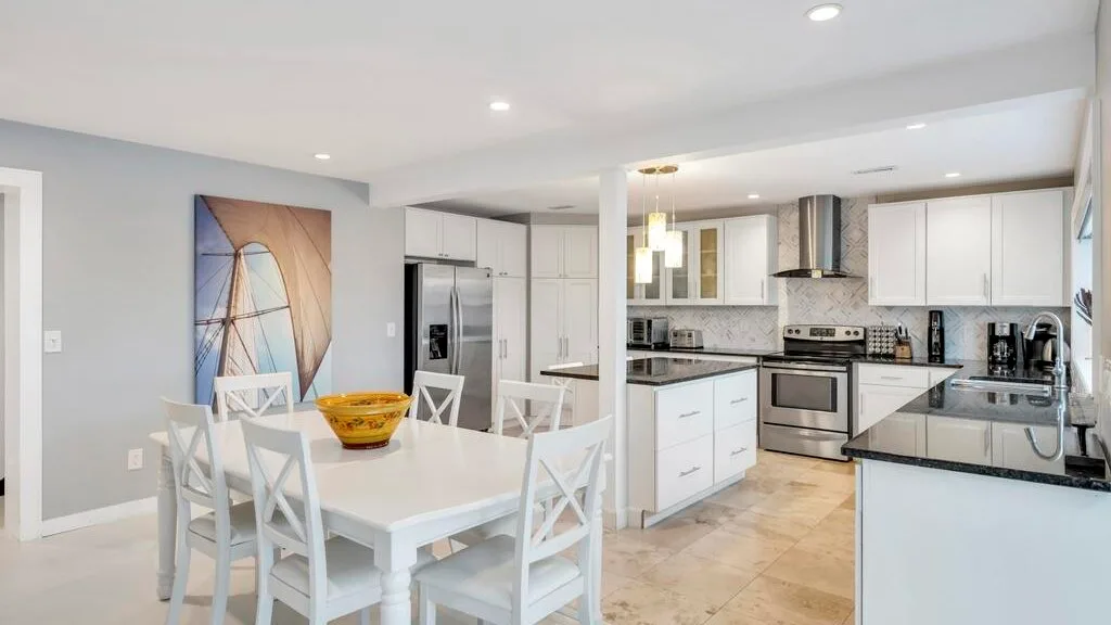 Una luminosa cocina y comedor con gabinetes blancos y una mesa de comedor.