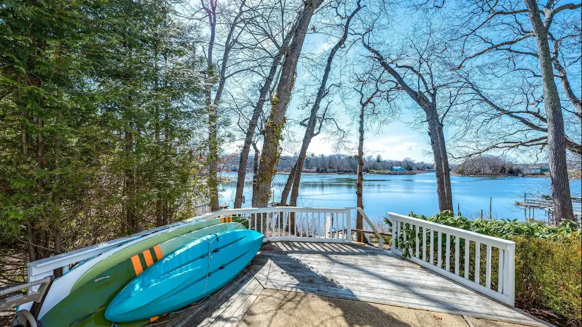 Una terraza junto al lago con kayaks junto a la barandilla da al agua.