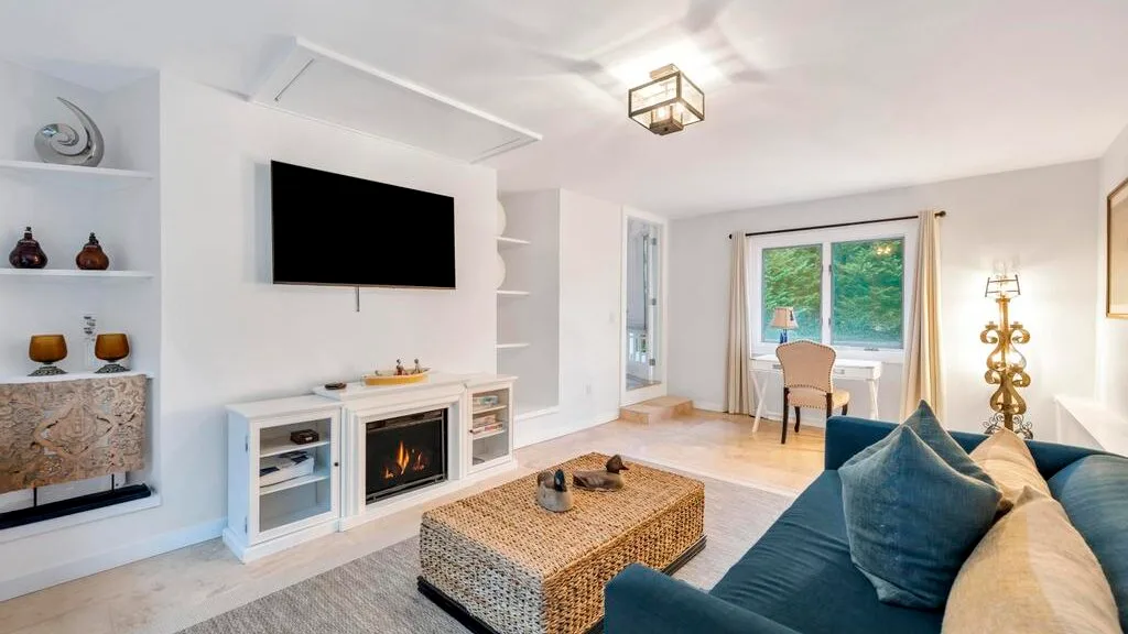 Sala de estar con asientos, una mesa de centro y un televisor montado en la pared.