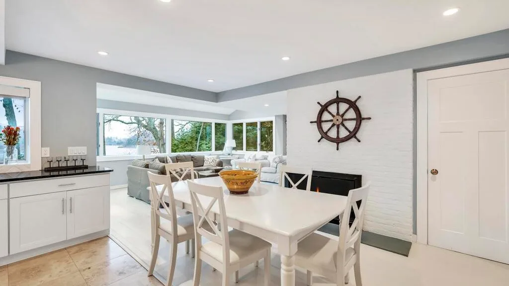 Un comedor luminoso con una mesa blanca y ventanas con vista a la vegetación.