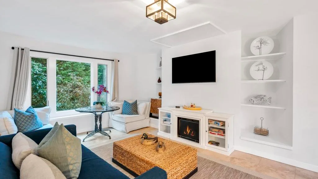 Una sala luminosa con asientos, una mesa de centro y un televisor en la pared.