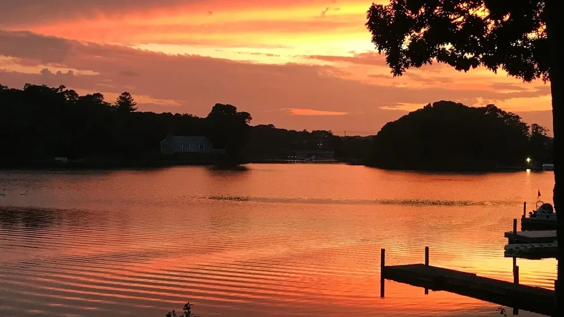Un lago al atardecer, con un muelle que se adentra en el agua.