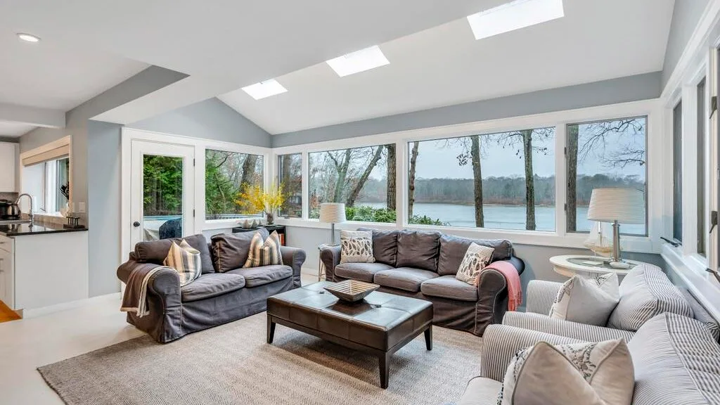 Una sala de estar luminosa con asientos junto a las ventanas y una mesa de centro.