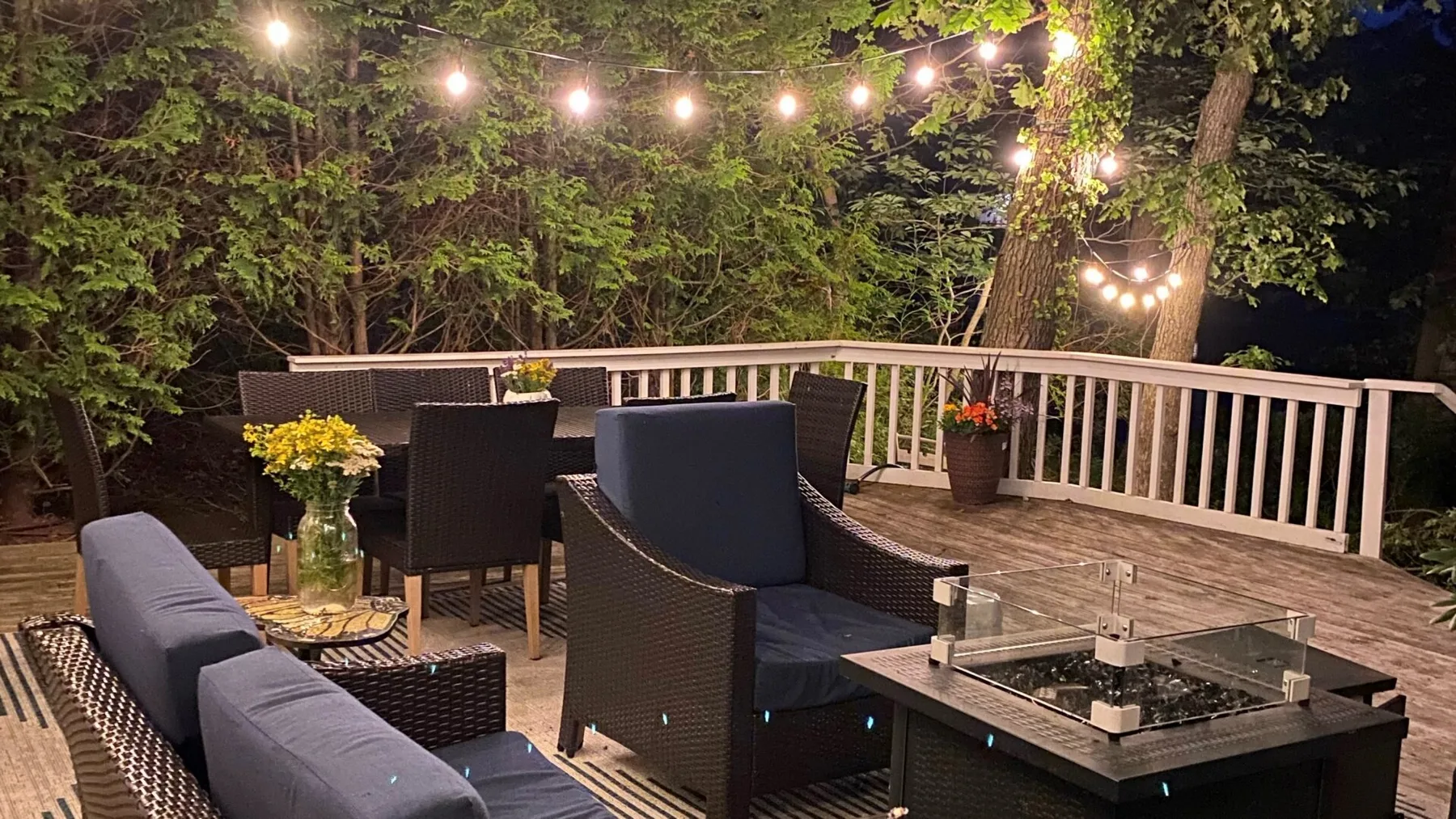 Una terraza exterior de noche con asientos acolchados y guirnaldas de luces.