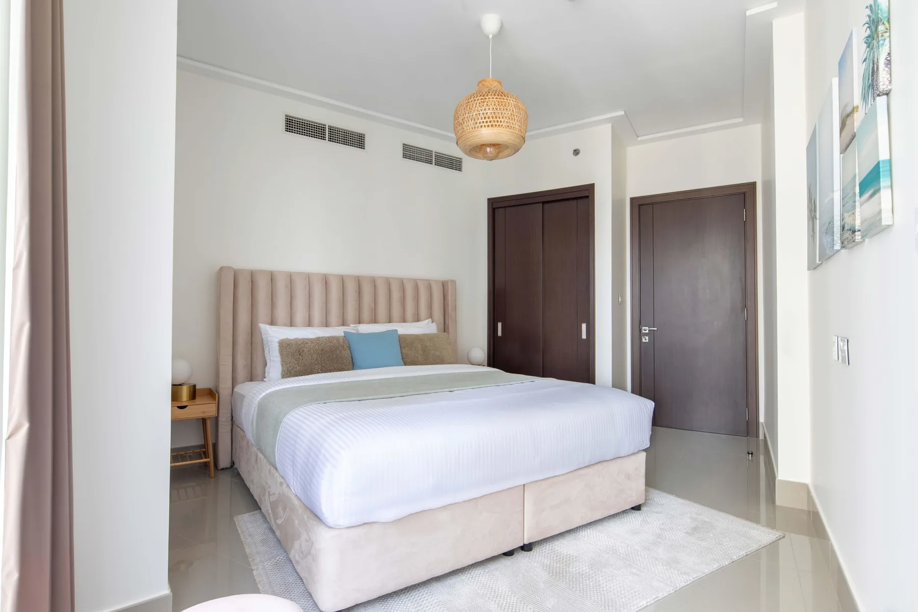 Un dormitorio luminoso con una cama tendida y puertas al fondo.