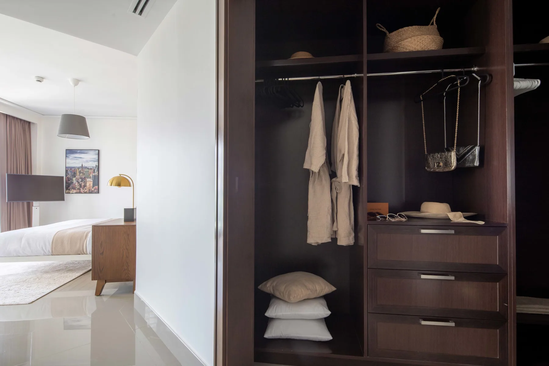Dormitorio con un armario abierto de madera oscura y ropa ordenada.