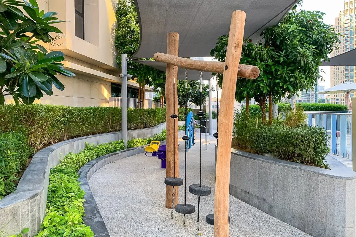 Zona de ejercicio al aire libre con barras de madera y senderos pavimentados.