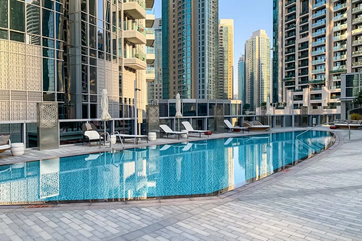 Una piscina rodeada de edificios altos y asientos en la terraza.